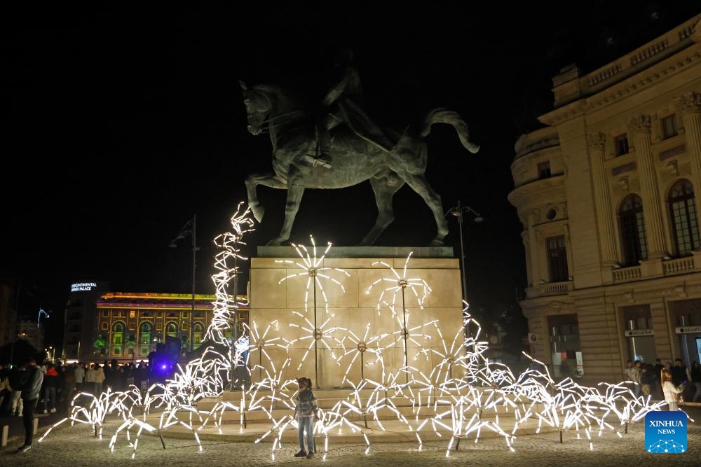 A child poses next to a light art installation during the Spotlight Festival in Bucharest, Romania, Oct. 10, 2025. (Photo: Xinhua)