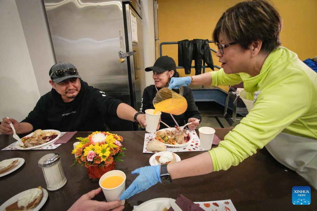A volunteer serves drinks to people as they enjoy Thanksgiving meals at the Union Gospel Mission in Vancouver, British Columbia, Canada, Oct. 10, 2025. The local charity served about 2,000 free meals on Friday to the local residents suffering from unemployment, rising living costs and a lack of affordable housing as part of an early Thanksgiving celebration. Canada's Thanksgiving Day falls on Oct. 13 this year. (Photo: Xinhua)