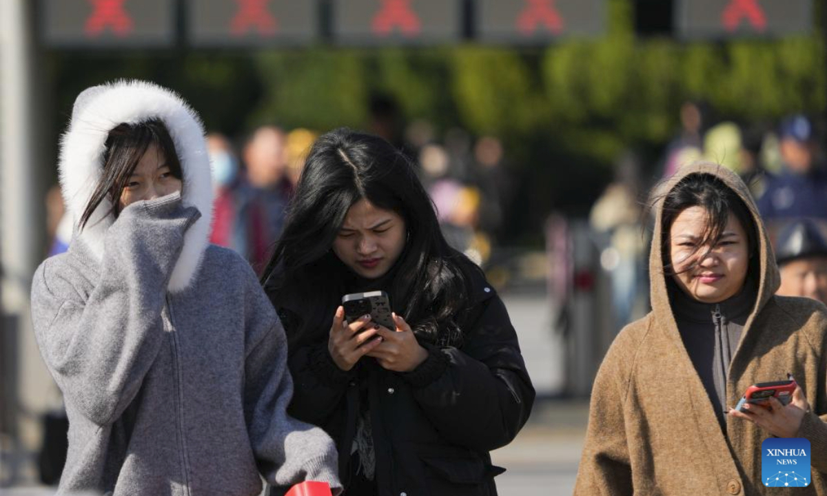 People walk against strong wind outside the east gate of the Temple of Heaven in Beijing, capital of China, Oct. 18, 2025. Affected by strong cold air, Beijing is hit by a cold wave. (Xinhua/Ju Huanzong)