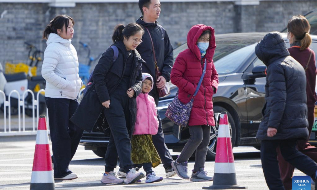 People wearing down jackets walk on a street in Beijing, capital of China, Oct. 18, 2025. Affected by strong cold air, Beijing is hit by a cold wave. (Xinhua/Ju Huanzong)