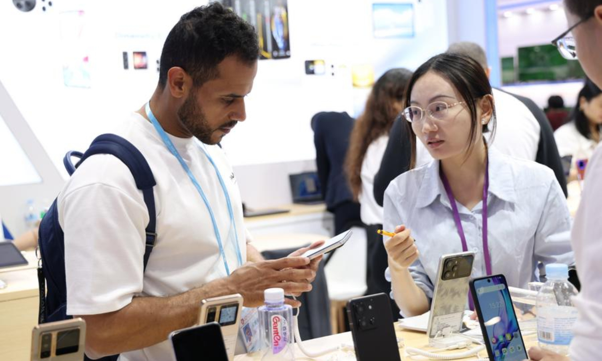 A buyer (L) learns about mobile phones during the 138th edition of the China Import and Export Fair in Guangzhou, south China's Guangdong Province, Oct. 15, 2025. (Xinhua/Lu Hanxin)