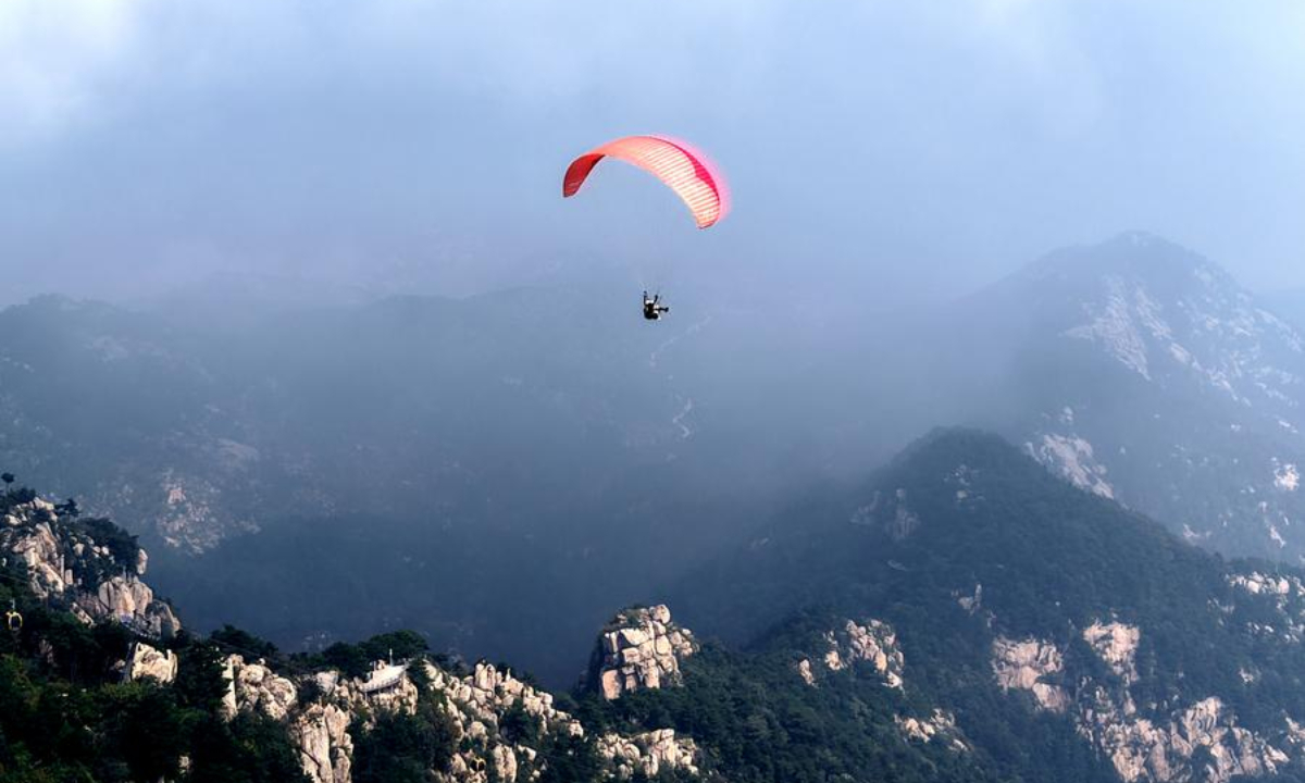 An aerial drone photo taken on Sept. 14, 2025 shows tourists experiencing paragliding at a scenic area in Linyi City, east China's Shandong Province. (Photo by Wu Jiquan/Xinhua)