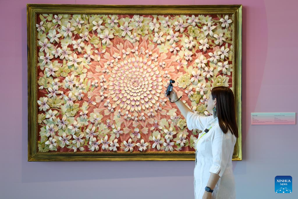 A female journalist records a video during Heritage Blossoms, Women Shine, a special exhibition celebrating the Global Leaders' Meeting on Women in Beijing, capital of China, Oct. 13, 2025. The Global Leaders' Meeting on Women was held in Beijing on Monday. (Xinhua/Liang Xu)