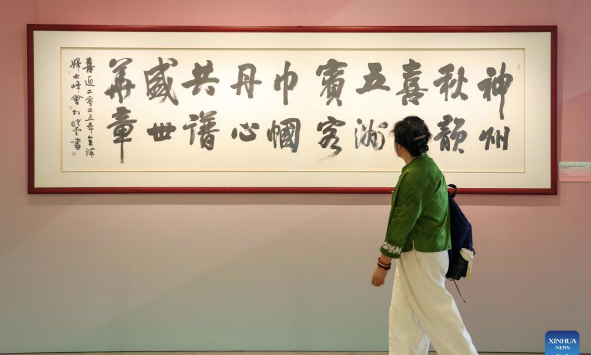A woman views an exhibit during Heritage Blossoms, Women Shine, a special exhibition celebrating the Global Leaders' Meeting on Women in Beijing, capital of China, Oct. 13, 2025. The Global Leaders' Meeting on Women was held in Beijing on Monday. (Xinhua/Liang Xu)