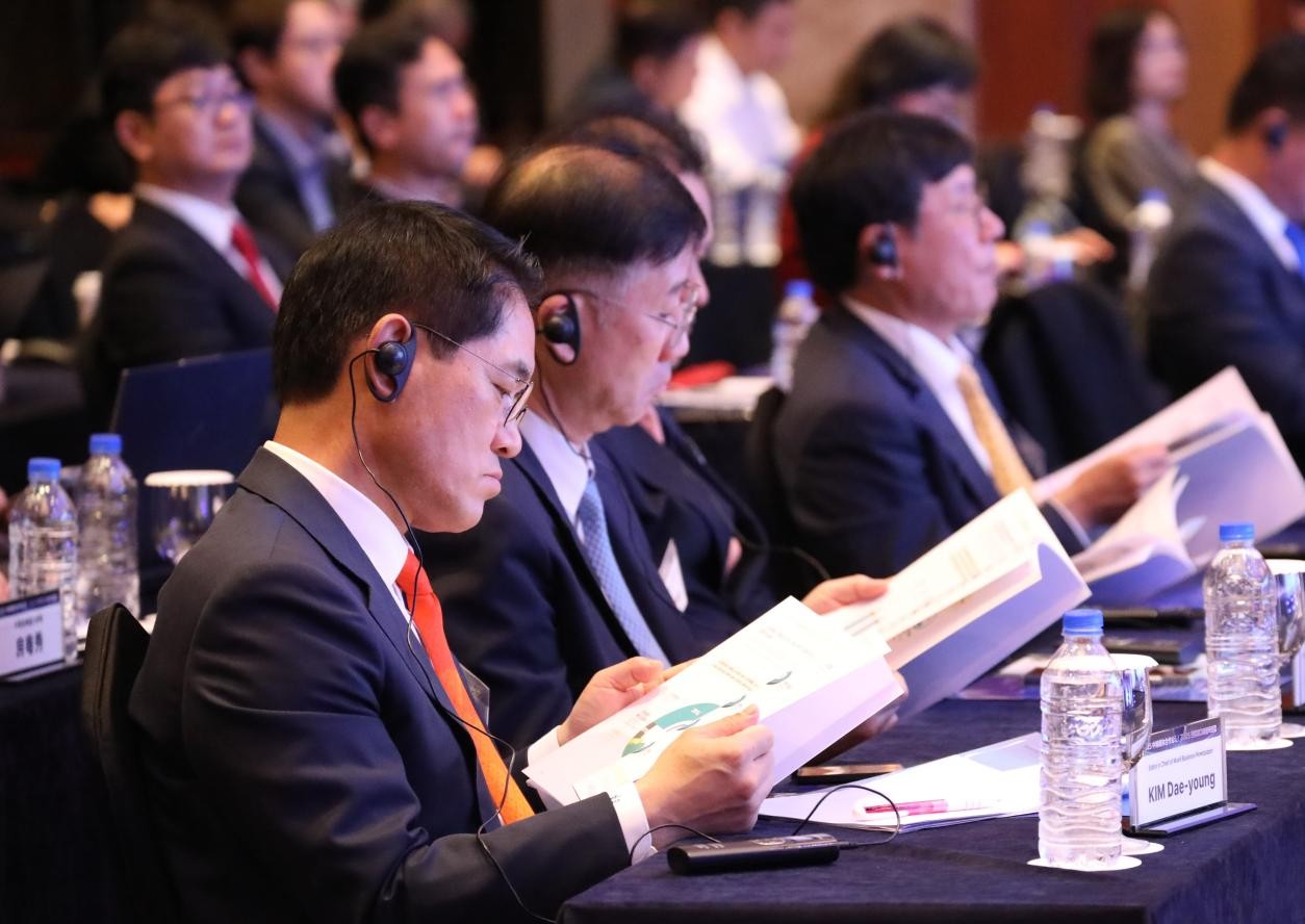 Participants examine the report booklet at the conference. Photo: People's Daily
