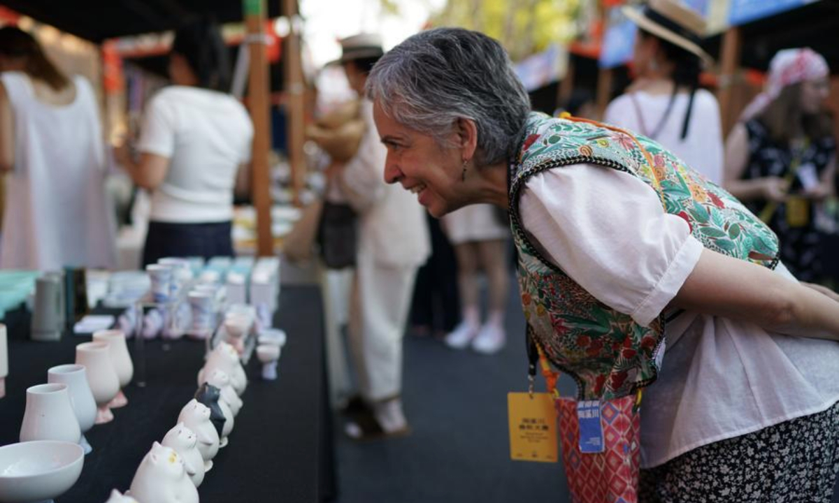 A foreign artist looks at ceramic works at a ceramic carnival held as a sideline event of the 2025 China Jingdezhen International Ceramic Expo in Jingdezhen, east China's Jiangxi Province, Oct. 17, 2025. (Xinhua/Zhou Mi)