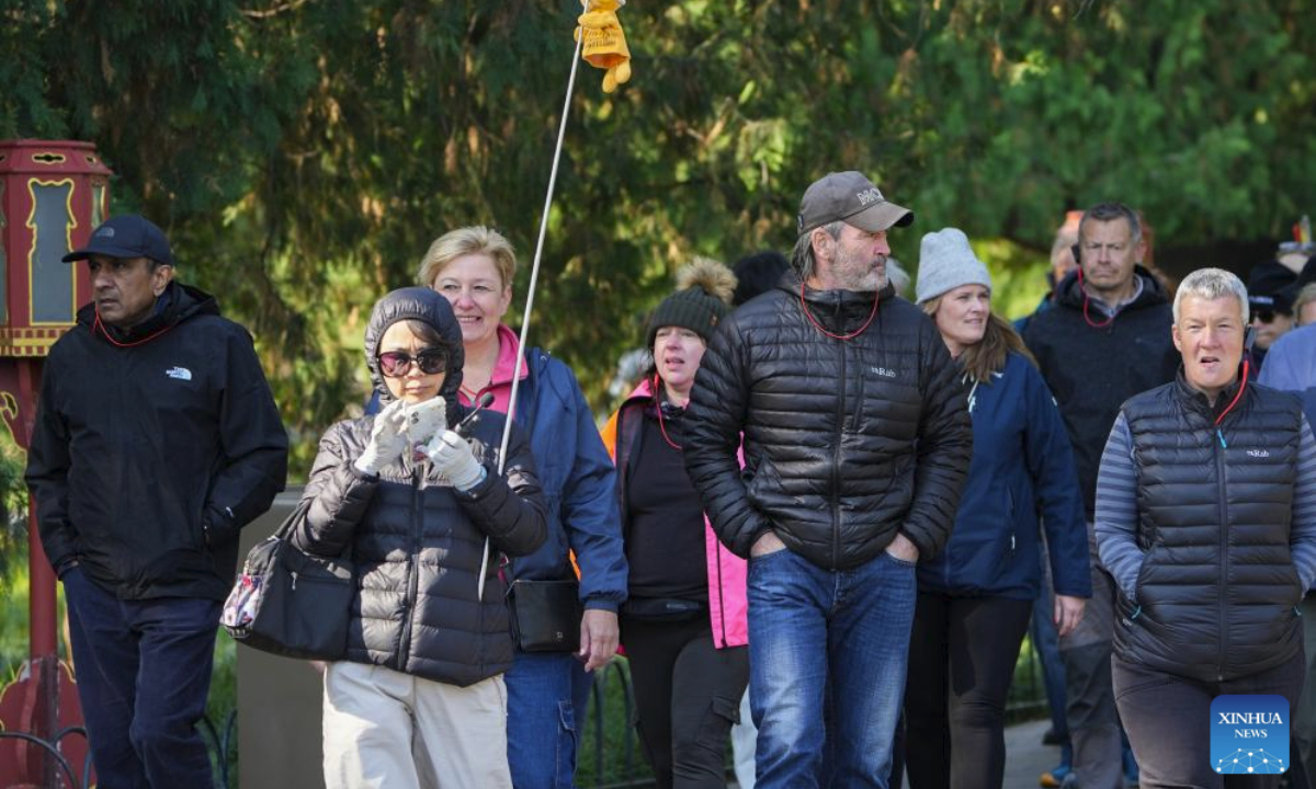 Foreigners wearing down jackets visit the Temple of Heaven in Beijing, capital of China, Oct. 18, 2025. Affected by strong cold air, Beijing is hit by a cold wave. (Xinhua/Ju Huanzong)