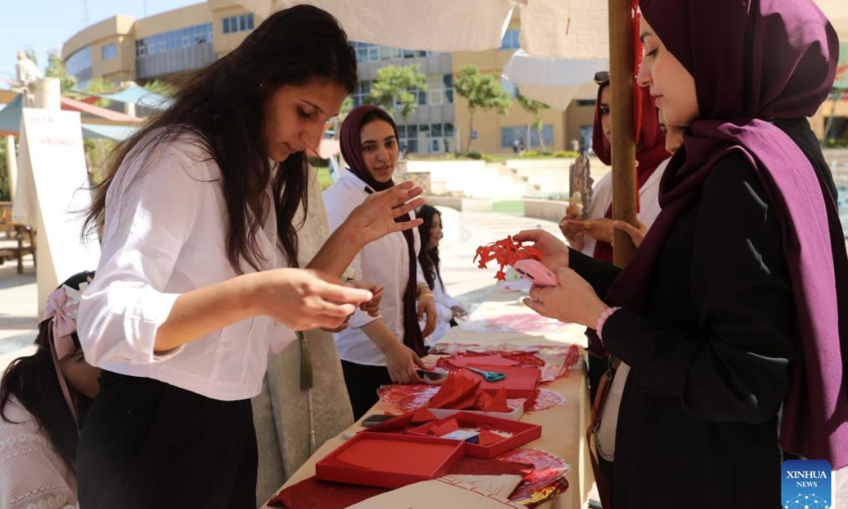 A student tries to make Chinese paper-cutting during a Chinese cultural event held at Badr University in Cairo, Cairo Governorate, Egypt, on Oct. 20, 2025. The Badr University in Cairo on Monday held a Chinese Culture Festival at its campus, with exhibition stands of Chinese calligraphy, paper-cutting and handicrafts, as well as activities including Chinese martial arts performance and ethnic costumes show, attracting lots of students and teachers. (Xinhua/Sui Xiankai)