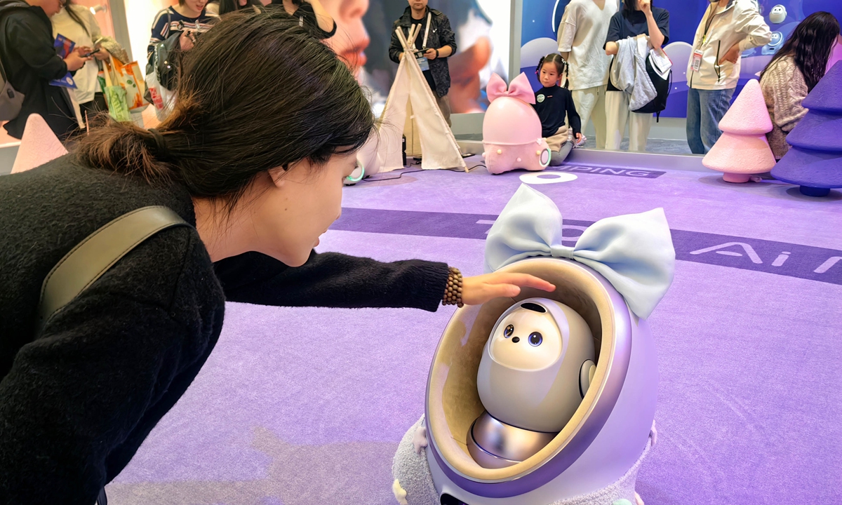 An AI-powered home companion robot makes its debut at the 2025 Appliance & Electronics World Expo (AWE2025) held in Shanghai on March 22, 2025, attracting a visitor to engage in an immersive interactive experience. Photo: VCG