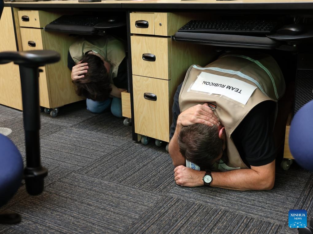 Staff members at the City of Los Angeles Emergency Operations Center follow instructions during an earthquake drill, practicing the Drop, Cover, and Hold On procedure in downtown Los Angeles, California, the United States, Oct. 16, 2025. More than 10 million Californians on Thursday took part in an annual statewide earthquake preparedness drill designed to raise public awareness and strengthen response capabilities for major quakes. (Photo by Qiu Chen/Xinhua)