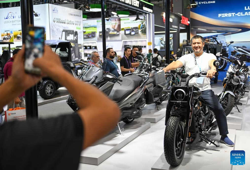 A buyer poses for a photo with a motorcycle at the motorcycle exhibition area of the 138th edition of the China Import and Export Fair in Guangzhou, south China's Guangdong Province, Oct. 19, 2025. The first phase of the 138th edition of the China Import and Export Fair, also known as the Canton Fair, concluded on Sunday. According to statistics from China Foreign Trade Center, about 157,900 overseas buyers from 222 countries and regions attended the event offline. (Photo: Xinhua)