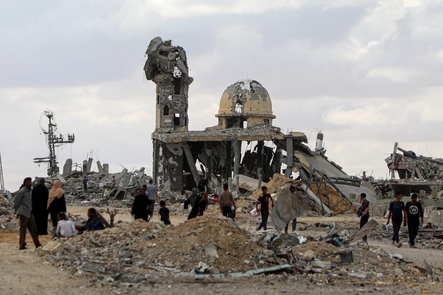 Palestinians walk past the rubble of destroyed buildings after returning to Khan Younis, in southern Gaza Strip, on Oct. 12, 2025. (Photo: Xinhua)