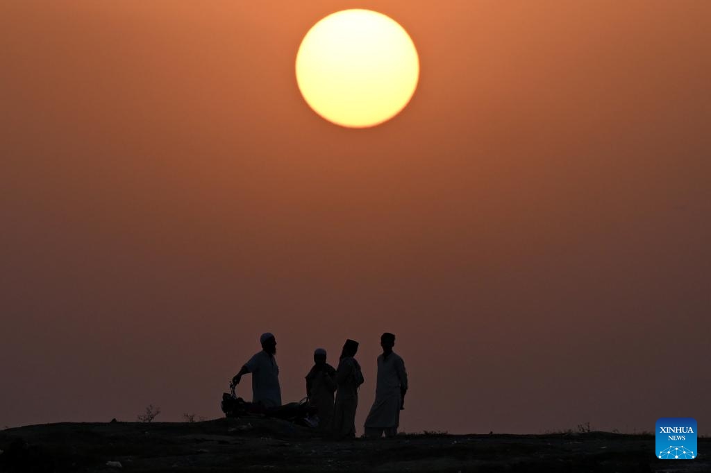 This photo taken on Oct. 19, 2025 shows the silhouette of people chatting with each other during sunset on the outskirts of Islamabad, capital of Pakistan. (Photo: Xinhua)