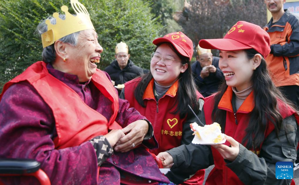 Volunteers hand a piece of cake to an elderly woman at a nursing home in Chengguan Town of Luoyang, central China's Henan Province, Oct. 28, 2025. A series of activities were held across the country to mark China's Chongyang Festival, which will fall on Oct. 29 this year. Also known as Seniors' Day in China nowadays, it highlights the public's care for elderly people. (Photo by Kang Hongjun/Xinhua)