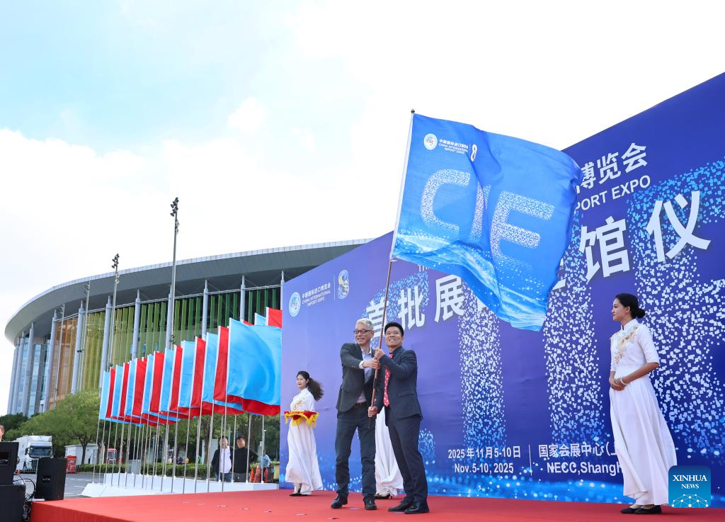 Representatives of exhibitors for the upcoming 8th China International Import Expo (CIIE) wave a flag during a ceremony marking the arrival of exhibits at the National Exhibition and Convention Center (Shanghai), the main venue for the CIIE, in east China's Shanghai, Oct. 23, 2025. The first batch of exhibits for the exhibition areas of Intelligent Industry and Information Technology, Food and Agricultural Products, and Medical Equipment & Healthcare Products of the 8th CIIE arrived at the National Exhibition and Convention Center (Shanghai) on Thursday. (Xinhua/Fang Zhe)