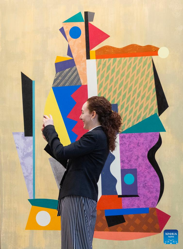 A woman takes photos in front of an artwork on display during the Art Toronto 2025 in Toronto, Canada, Oct. 23, 2025. Featuring over 100 international galleries, installations, project spaces and more, the art fair is held here from Oct. 23 to 26. (Photo by Zou Zheng/Xinhua)