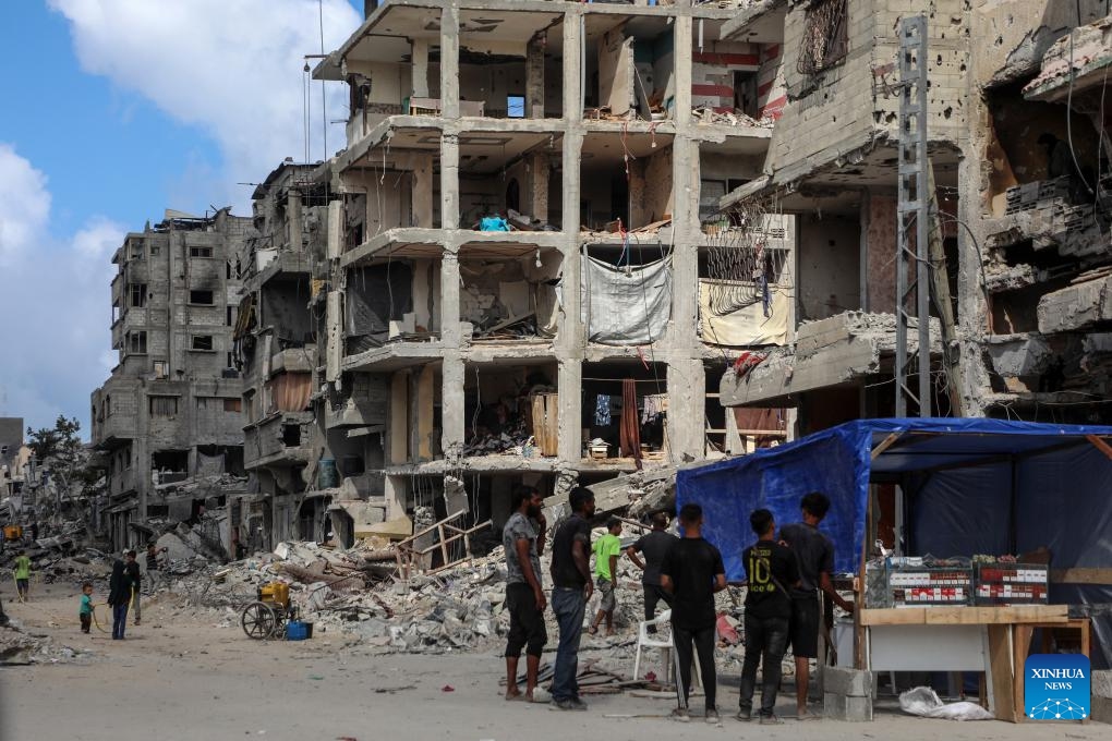 Palestinians gather at a street vendor under the destroyed buildings in Jabalia, northern Gaza Strip, Oct. 24, 2025. The United Nations estimates that approximately 92 percent of all residential buildings in Gaza -- around 436,000 homes -- have been damaged or destroyed since the start of the conflict. According to the UN, at least 1.9 million people across the Gaza Strip have been displaced during the war. (Photo: Xinhua)