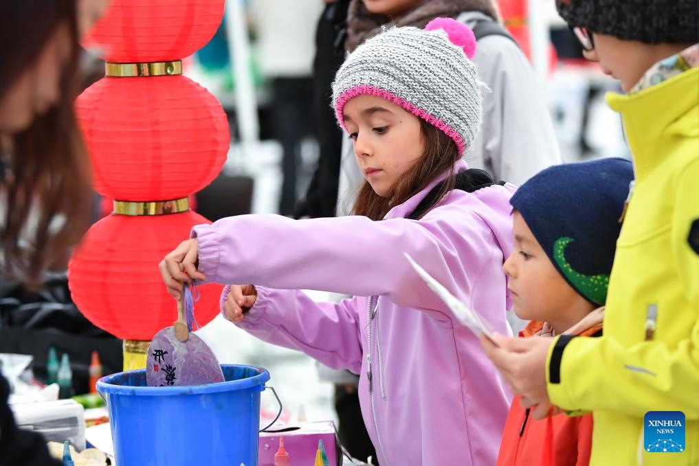 A child tries lacquer fan crafting during the Meet China cultural festival at Waisenhaus Square in Bern, the capital of Switzerland, Oct. 25, 2025. The festival was held here on Saturday to celebrate the 75th anniversary of the establishment of diplomatic relations between China and Switzerland and the 76th anniversary of the founding of the People's Republic of China. It spotlighted a variety of performances including Chinese martial arts, acrobatics, and Swiss alpine horn, as well as about 20 cultural experiences such as sachet making and lacquer fan crafting. (Photo: Xinhua)