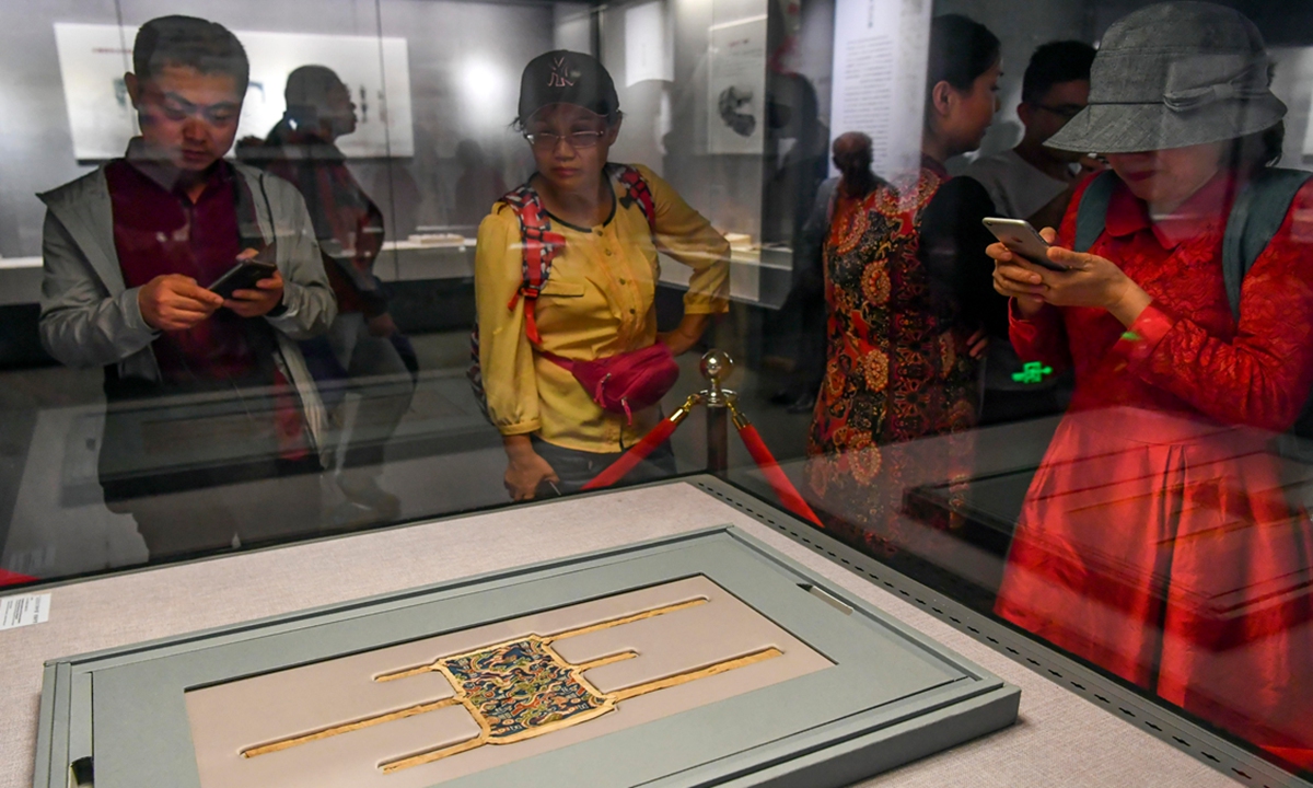 People gather around a piece of brocade armguard unearthed 
from the Niya site at the Xinjiang Museum. Photo: VCG