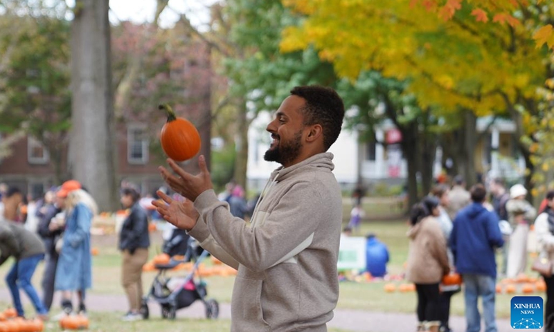 A man throws a pumpkin up in the air at the Governors Island in New York, the United States, on Oct. 25, 2025. A festival was held at the Governors Island in New York on Saturday, attracting locals and visitors to celebrate the fall harvest with various family-friendly activities.  (Photo: Xinhua)