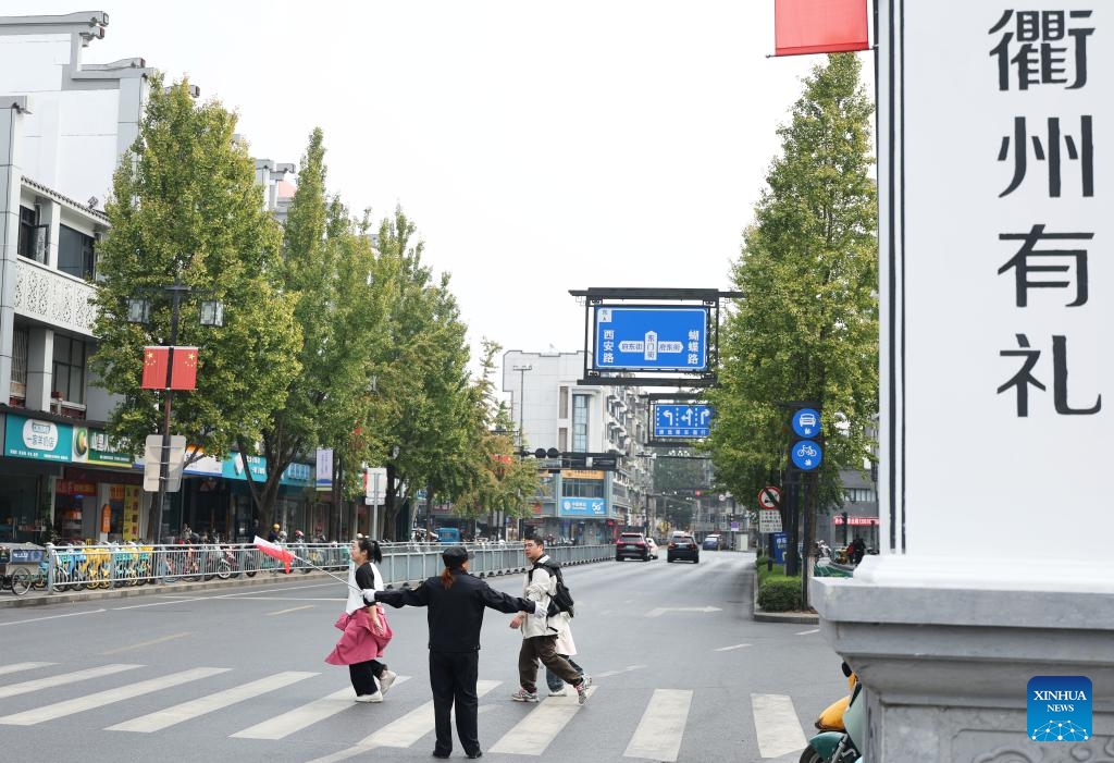 A volunteer guides pedestrians to go across the road in Quzhou, east China's Zhejiang Province, Oct. 26, 2025. In recent years, Quzhou has been fostering a harmonious living environment by promoting Chinese etiquette education to the public and putting the idea of good-mannered into its governmental service. (Photo: Xinhua)