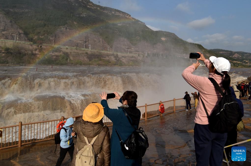 Tourists take photos of a rainbow over the Hukou Waterfall in Jixian County, north China's Shanxi Province, Oct. 27, 2025. (Photo: Xinhua)