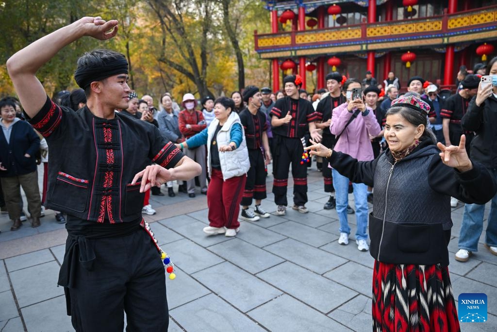 A performer from a Yunnan dance and opera troupe interacts with a citizen during a flash mob event at Renmin park in Urumqi, northwest China's Xinjiang Uygur Autonomous Region, Oct. 27, 2025. A flash mob event featuring ethnic dances was held here on Monday. (Photo: Xinhua)