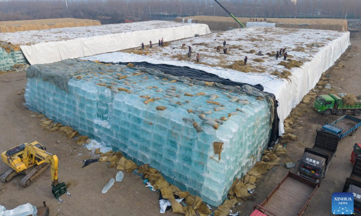 An aerial drone photo taken on Nov. 24, 2025 shows staff members removing the covering on the ice cubes at an ice storage site for the Harbin Ice-Snow World in Harbin, northeast China's Heilongjiang Province. The 27th edition of the Harbin Ice-Snow World, a renowned seasonal theme park in Harbin, will officially begin construction on Nov. 25 this year. (Xinhua/Xie Jianfei)