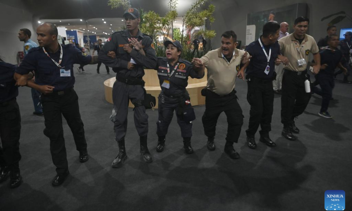 Security personnel form a human chain to guide people evacuating the venue of the 30th United Nations Climate Change Conference (COP30) after a fire broke out in Belem, Para state, Brazil, Nov. 20, 2025. A fire broke out on Thursday in a pavilion at the ongoing 30th UN Climate Change Conference in the Brazilian city of Belem, prompting evacuations by the fire department, according to local authorities. (Photo by Lucio Tavora/Xinhua)