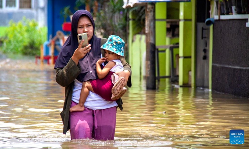 A mother makes a phone call while wading through floodwater with her daughter after heavy rain and overflow of Citarum river hit at Bojongsoang in Bandung, West Java, Indonesia, Nov. 1, 2025. (Photo: Xinhua)