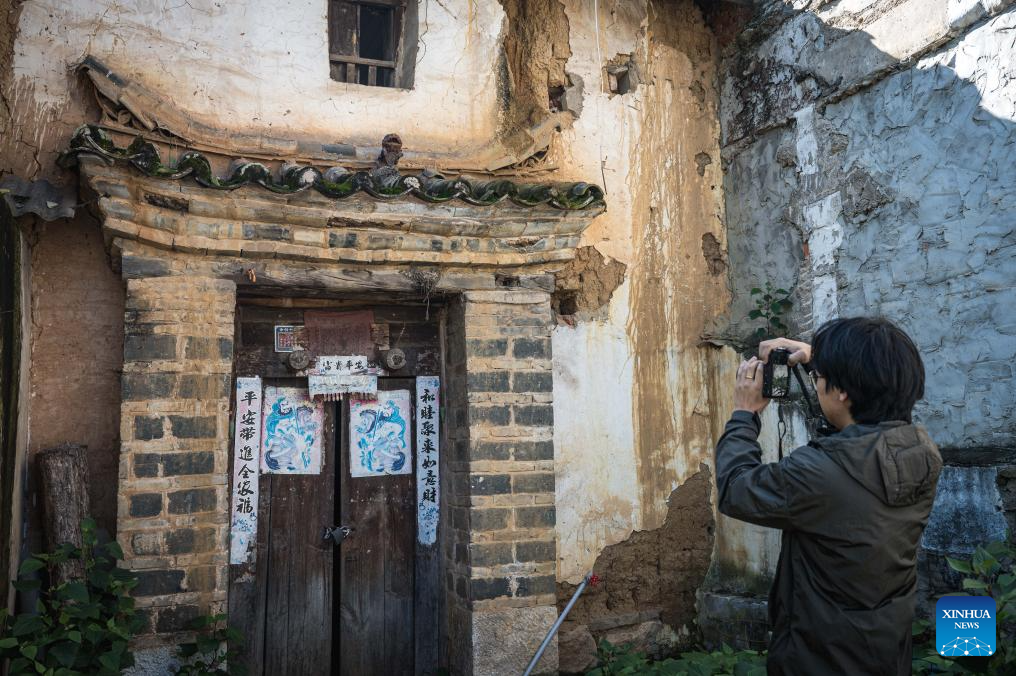 Zhang Hang collects images of Wamao with his camera at Haiyan Village in Kunming, southwest China's Yunnan Province, Nov. 12, 2025. Zhang Hang, 32, is an inheritor of the Kunming Wamao-making technique and the founder of the Heart Chamber Wamao Museum.

Wamao, a cat-shaped pottery artifact originating in Yunnan, combines practical design with folk beliefs. Traditionally mounted on eaves or lintels, it was believed to drive away evil spirits and bring peace to the household. In 2023, Wamao was listed as one of Yunnan's provincial intangible cultural heritage items.

Zhang first encountered Wamao in 2012, when he was studying folk art design at Yunnan Arts University. I was drawn to its expressive artistic form, Zhang said. I wanted to integrate its unconstrained style into modern design.

Since then, searching for old Wamao has become part of his daily life. He has wandered through old city markets and construction sites, from cities of Dali and Lijiang to the outskirts of Kunming, chasing traces of the clay guardians.

In 2019, Zhang founded the Wamao museum to promote the craft through exhibitions, hands-on classes, and cultural tours. Visitors can take part in Wamao-making workshops, Wamao placement ceremonies, and field trips to traditional villages.

In his studio, Zhang mixes clay, shapes the cat's head and body, and then fires it in a kiln after drying. The belly of the cat is left hollow, with its mouth and tail connected, symbolizing the idea of swallowing evil and releasing blessings.

Skilled artisans can complete a Wamao in a week, but Zhang said the true challenge lies in merging tradition with innovation.

It sometimes takes a month to create one that feels right, he said. The goal is to help this ancient craft find new meaning in modern society.

As urbanization changes the landscape of Kunming, many old houses have disappeared. Zhang hopes his work will help preserve the memory of the Wamao and its cultural spirit.

As old houses crumble, I hope the chamber of my heart will serve as a new home for Wamao, he said. (Xinhua/Wang Guansen)