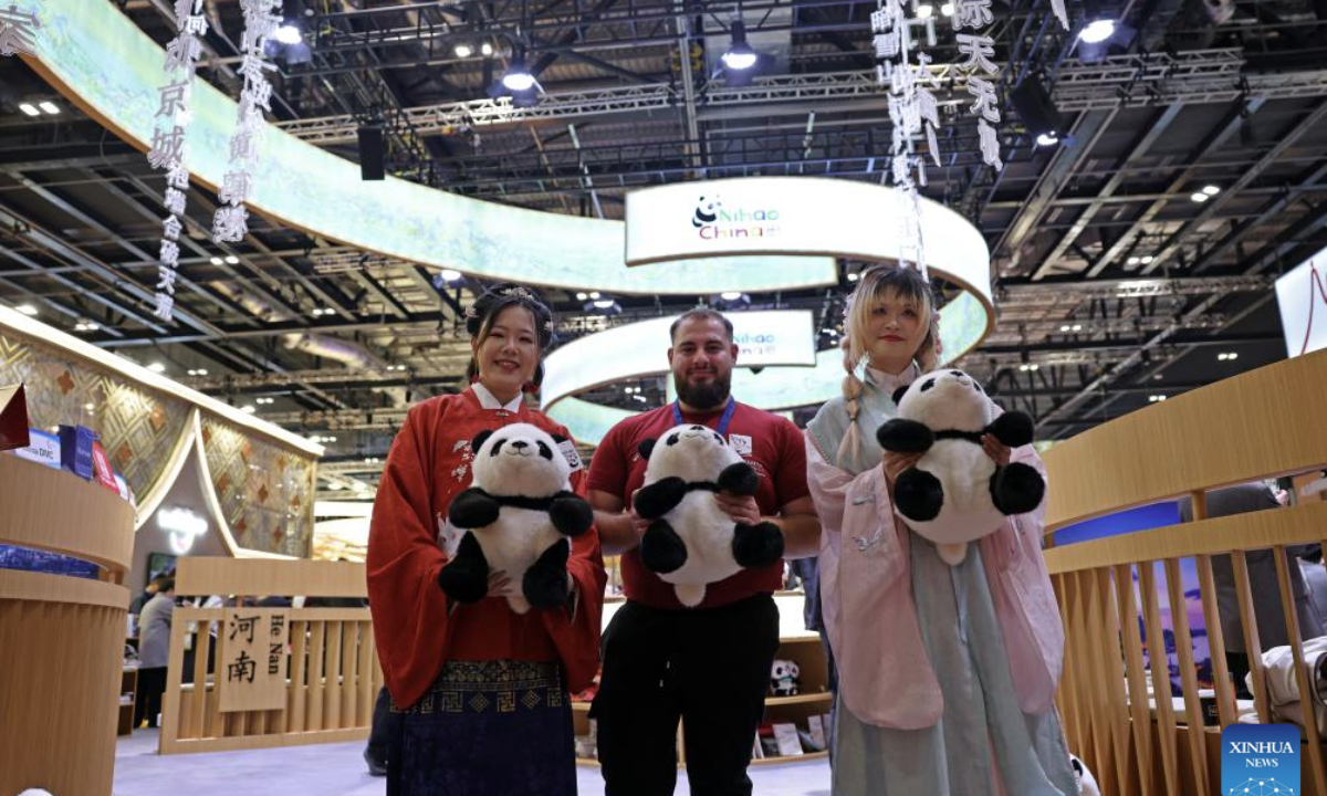 A man poses for photos with staff members at the China pavilion of the World Travel Market (WTM) London 2025 in London, Britain, Nov. 4, 2025. The WTM London 2025 opened on Tuesday, with the China pavilion drawing attention for its abundant tourism resources and cultural appeal. (Xinhua/Li Ying)