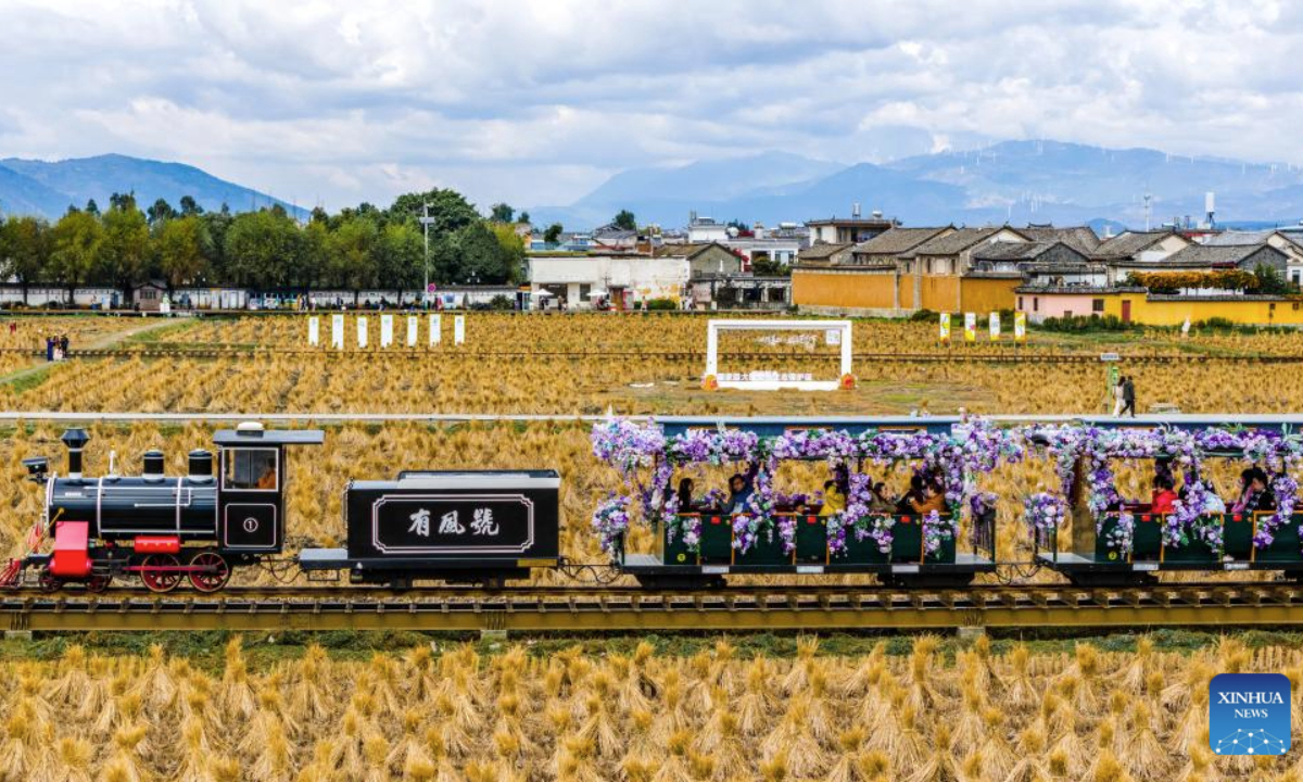 A drone photo taken on Nov. 24, 2025 shows tourists taking a sightseeing train in Xizhou old town of Dali City, southwest China's Yunnan Province. (Xinhua/Hu Chao)