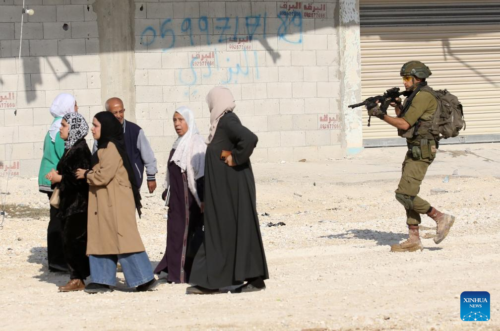 An Israeli soldier tries to prevent Palestinians from reaching their houses in Nur Shams refugee camp in the West Bank city of Tulkarm, Nov. 18, 2025. Palestinians took part in a demonstration demanding the right to return to their houses at the entrance of Nur Shams refugee camp, while Israeli soldiers assaulted the crowd and forced them to leave the area. (Photo by Nidal Eshtayeh/Xinhua)