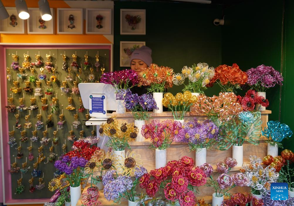 A vendor sells gifts at the holiday market at Union Square in New York, the United States, on Nov, 19, 2025. More than 150 booths selling unique gifts created by local craftsmen and artists filled Union Square in New York city for its annual Holiday Market, which runs from November 13 to December 24, 2025. (Xinhua/Zhang Fengguo)