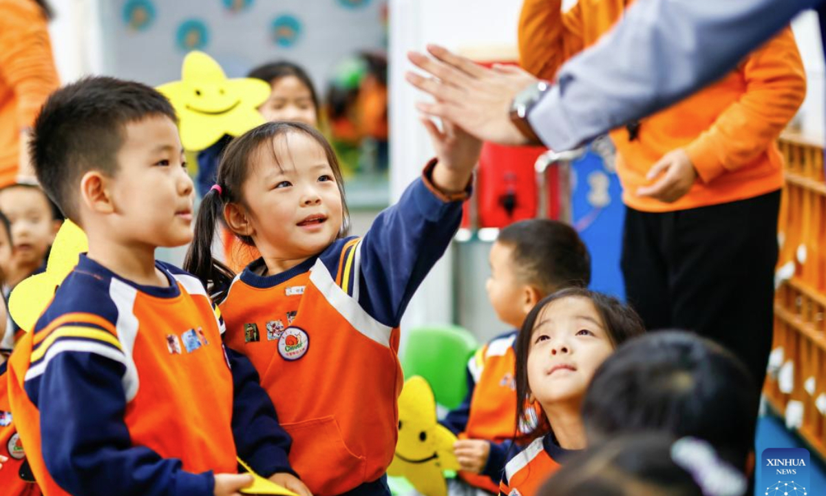 Volunteers and children greet each other to celebrate the upcoming World Hello Day, which falls on Nov. 21 annually, at a kindergarten in Binhai New Area, north China's Tianjin Municipality, Nov. 20, 2025. (Photo by Du Penghui/Xinhua)