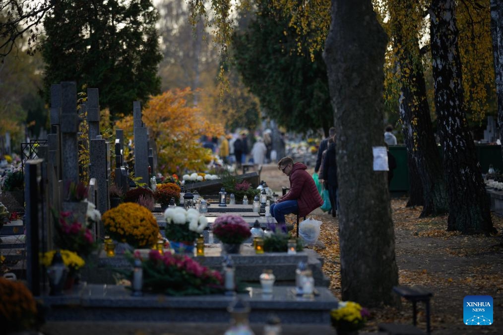 A man sits quietly by a grave to commemorate All Saints' Day at a cemetery in Warsaw, Poland on Nov. 1, 2025. Saturday marks All Saints' Day in Poland, when people traditionally return home to reunite with family members and visit cemeteries to honor their ancestors. (Photo: Xinhua)