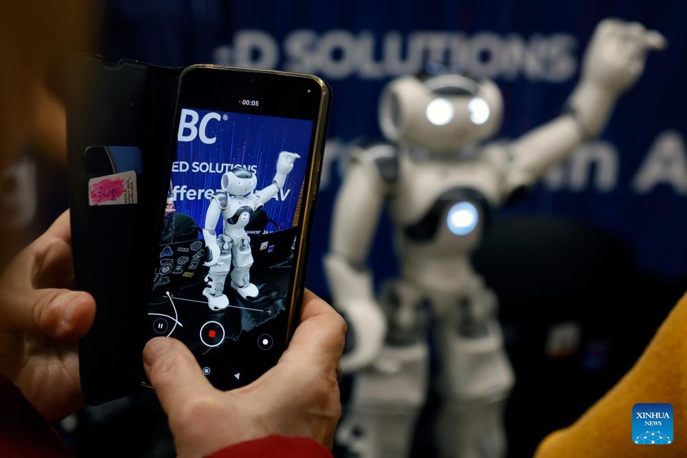 A visitor takes pictures of a humanoid robot during the 4th edition of the Robofest, a technology festival, at the Politehnica University of Bucharest in Bucharest, Romania, Nov. 1, 2025. The three-day festival including the 16th edition of the Robochallenge is held here from Oct. 31 to Nov. 2. (Photo: Xinhua)