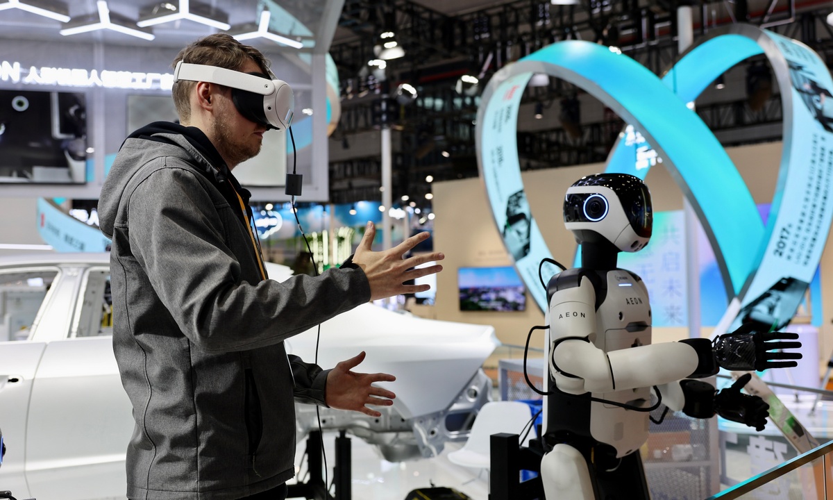 A foreign visitor immerses in a virtual reality experience and gestures toward a robot at the ongoing 8th China International Import Expo in Shanghai on November 4, 2025. Photo: Chen Xia/GT