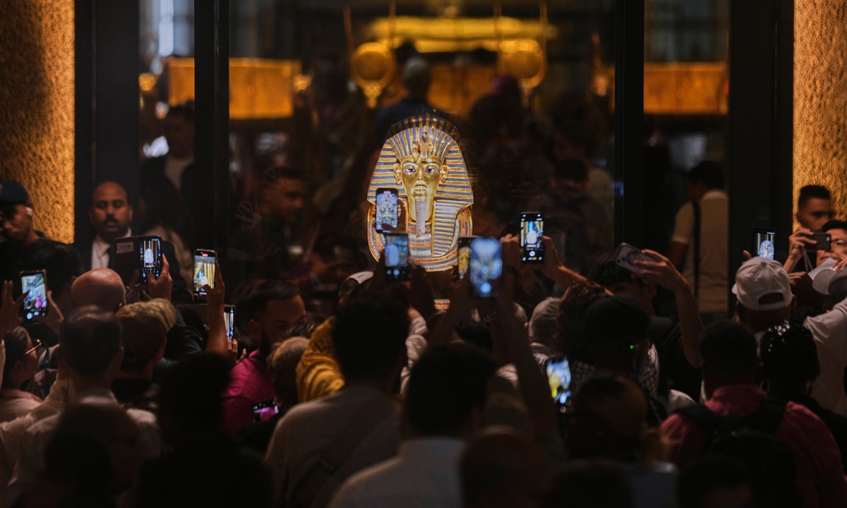 People hold mobile devices in front of the golden burial mask of King Tutankhamun during the first day for visitors after the official opening of the Grand Egyptian Museum in Giza, Egypt, on November 4, 2025. Photo: VCG