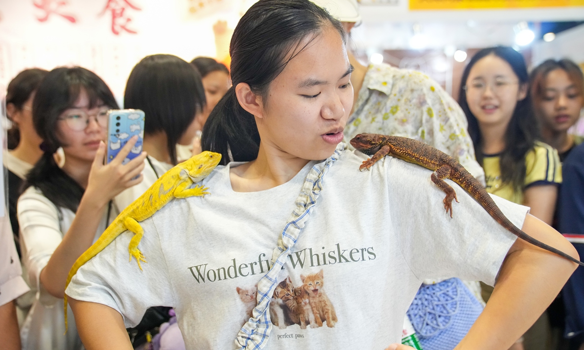 A visitor poses with two bearded dragons perched on their shoulders at the 2025 Hongwei World Pet Expo on August 9, 2025, Nanning, South China's Guangxi Zhuang Autonomous Region. Photo: VCG