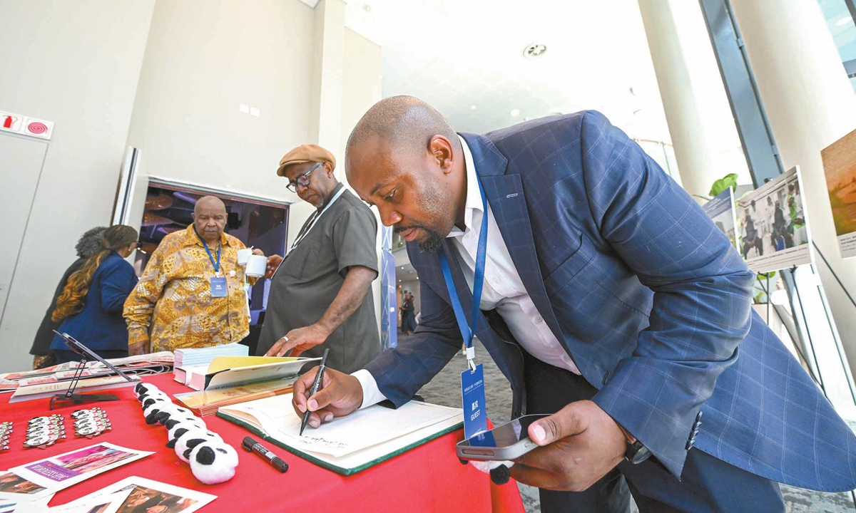 A guest writes down his thoughts in a message book at the photo exhibition in Johannesburg, South Africa, on November 5, 2025. Photo: Chen Tao/GT