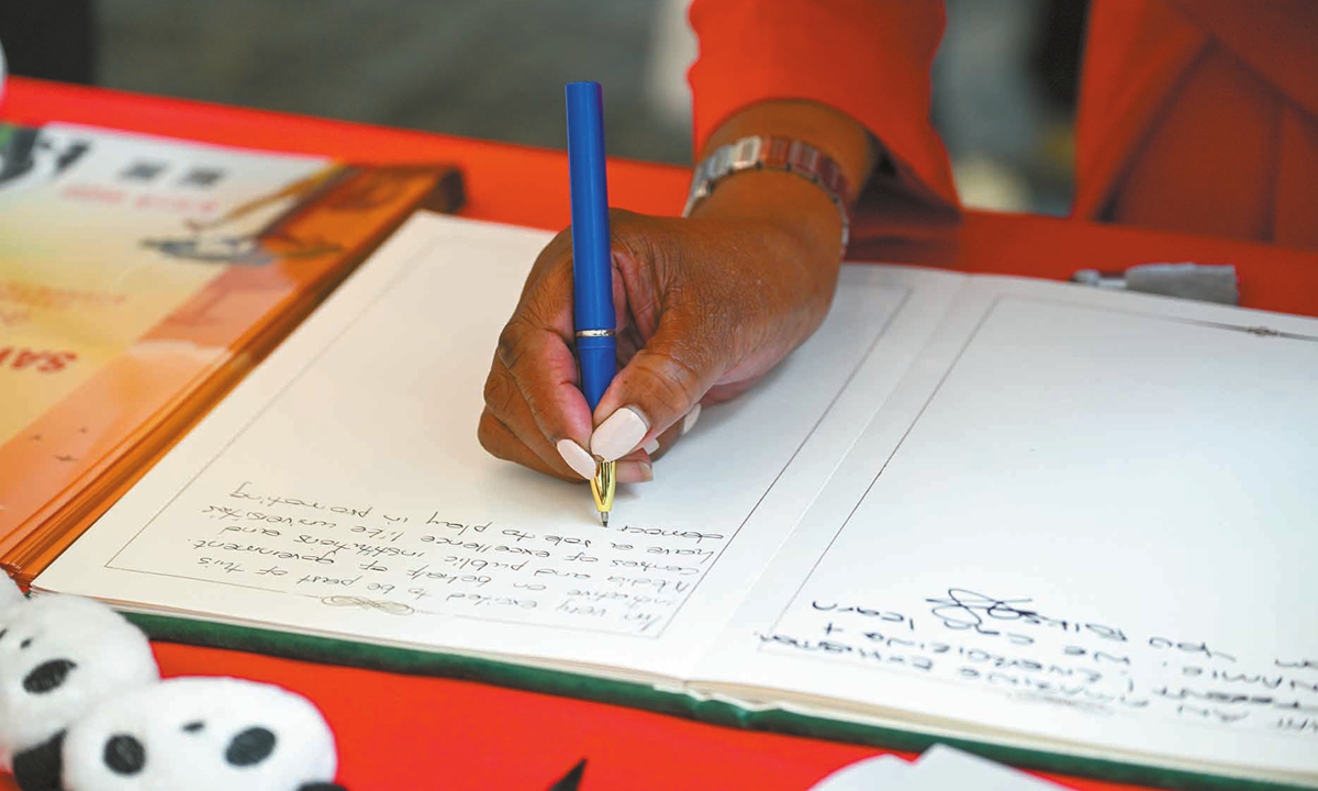 A guest writes down her thoughts in a message book at the photo exhibition in Johannesburg, South Africa, on November 5, 2025. Photo: Chen Tao/GT