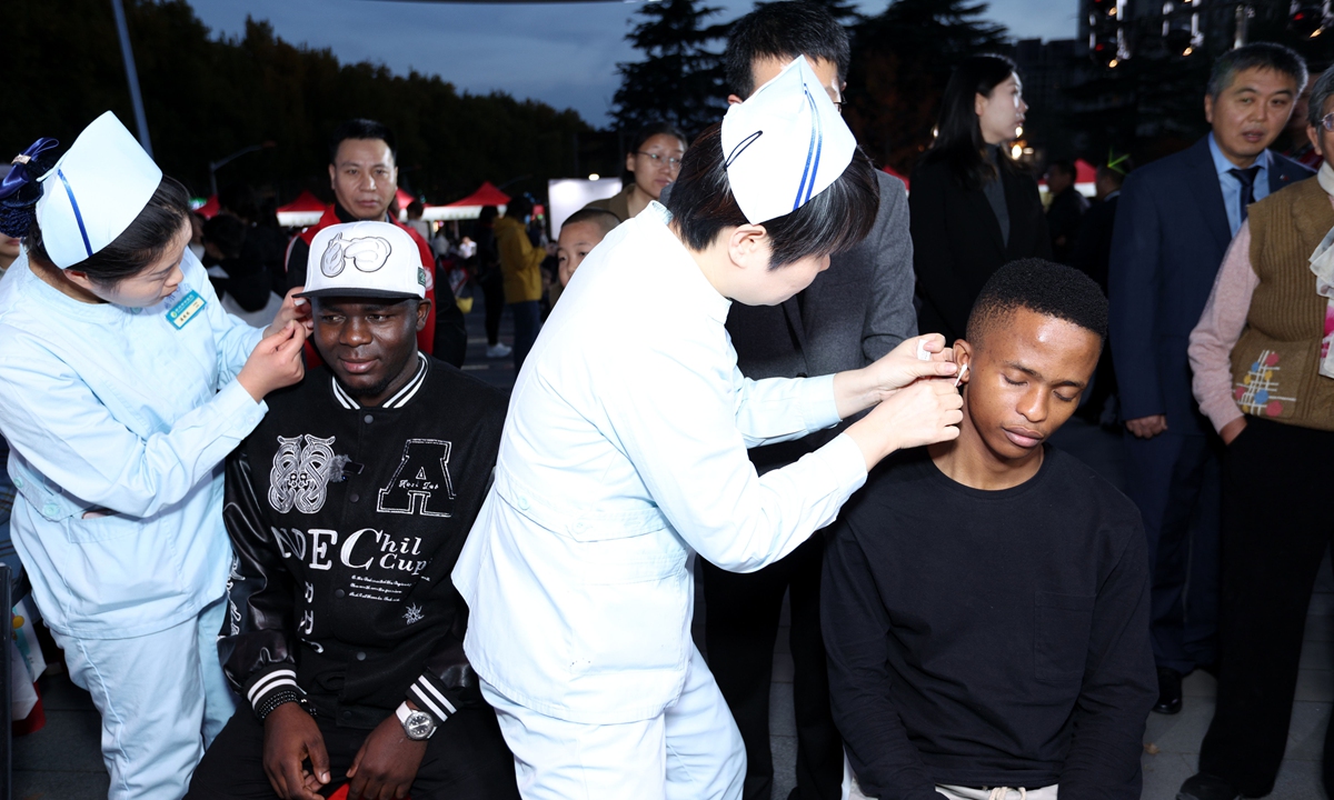 Foreigners experience ear point therapy at the night market in Zhengzhou, Central China's Henan Province on November 1, 2025. Photo: VCG