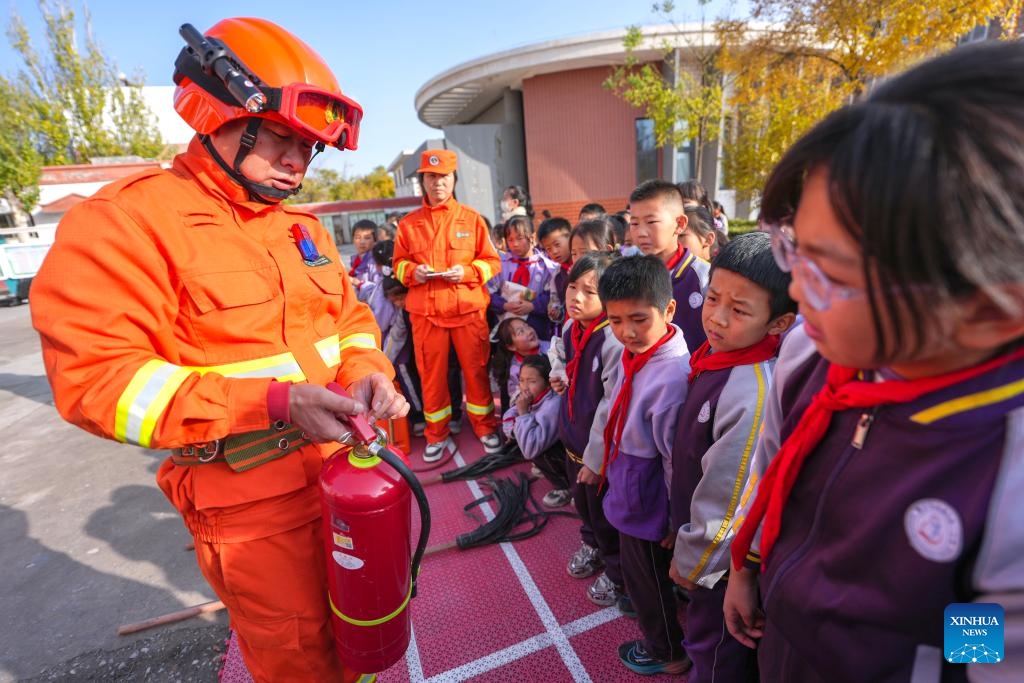A staff member of Ningxia Helan Mountain National Nature Reserve Administration explains the use of fire extinguisher to students at a primary school in Yinchuan, northwest China's Ningxia Hui Autonomous Region, Nov. 7, 2025. Currently, the risk of forest fire is high across the Helan Mountain. Staff members of local nature reserve administration have rolled out a series of educational activities with the theme of forest fire prevention, aiming to enhance students' safety awareness via lectures, equipment demonstrations, and hands-on experiences. (Xinhua/Yang Zhisen)
