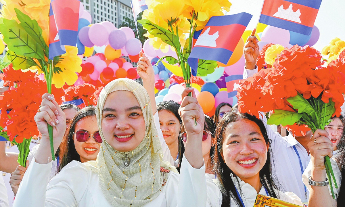 Women hold up flowers and national flags during a ceremony marking Cambodia's 72nd Independence Day celebrations at the Independence Monument in Phnom Penh on November 9, 2025. Photo: VCG