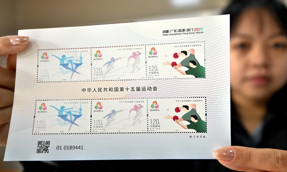 A postal worker shows off commemorative stamps for the 15th Chinese National Games in Handan, Hebei Province, on November 9, 2025. China Post issued a set of three commemorative stamps for the National Games which opened on Sunday. The stamps show three sports: artistic swimming, fencing, and table tennis. Photo: VCG