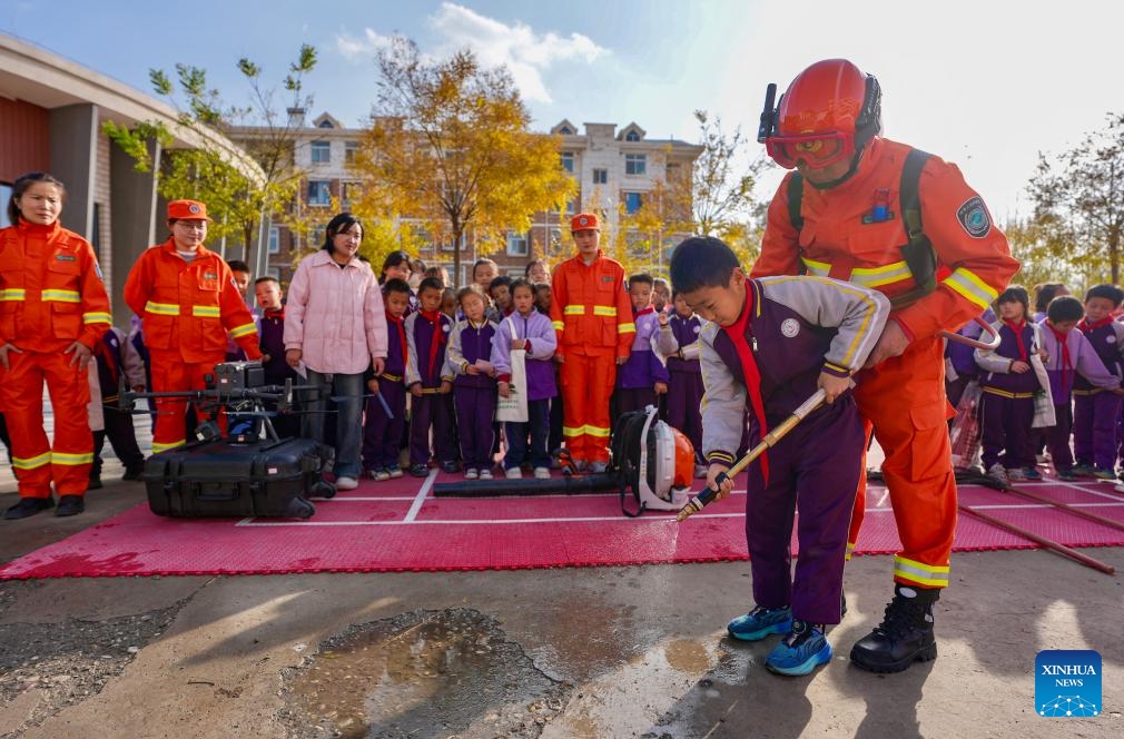 A staff member of Ningxia Helan Mountain National Nature Reserve Administration instructs a student to use equipment for forest fire prevention at a primary school in Yinchuan, northwest China's Ningxia Hui Autonomous Region, Nov. 7, 2025. Currently, the risk of forest fire is high across the Helan Mountain. Staff members of local nature reserve administration have rolled out a series of educational activities with the theme of forest fire prevention, aiming to enhance students' safety awareness via lectures, equipment demonstrations, and hands-on experiences. (Xinhua/Yang Zhisen)