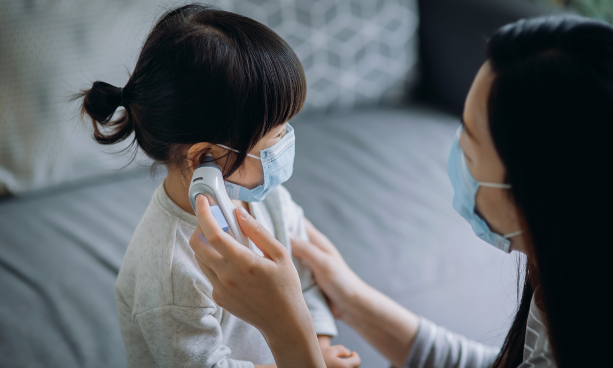 A mother checks her sick daughter's temperature with an electronic thermometer. Photo: VCG
