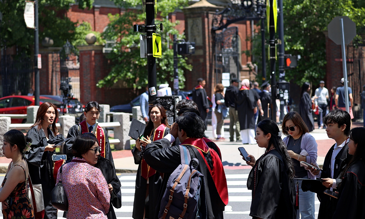 Harvard University graduates take photos outside of Harvard Yard on May 27, 2025. Photo：VCG